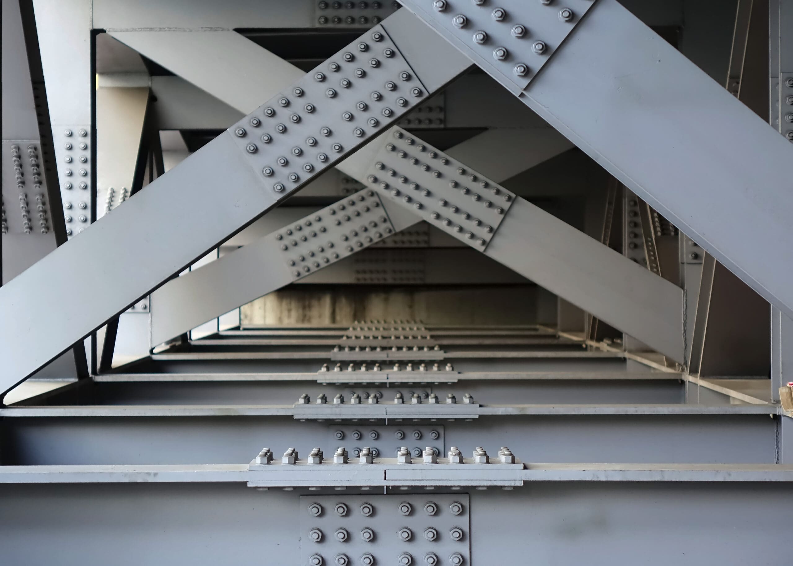 The underside of a bridge with large steel girders, bolts and nuts