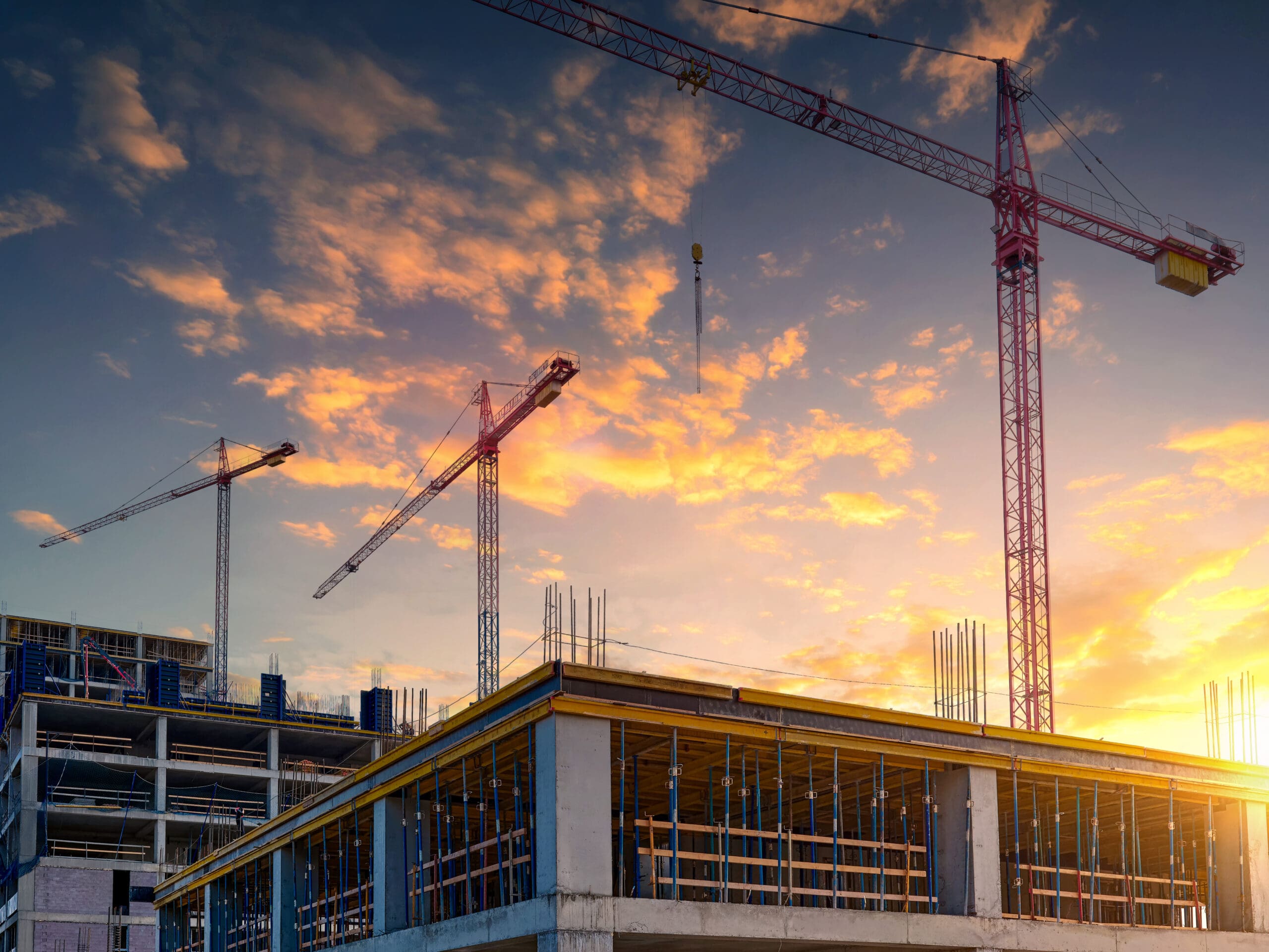 Construction of a new residential complex.Several high-rise cranes against the backdrop of a beautiful sunset sky.