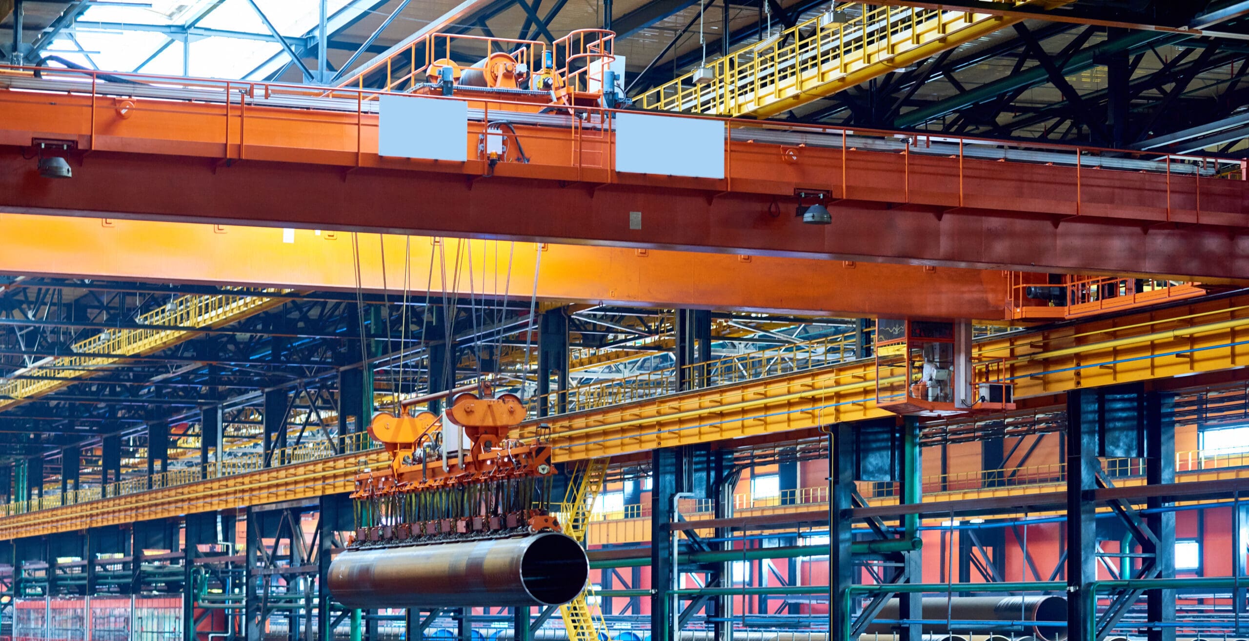 Grue à pont puissante transportant un tuyau au-dessus d’une usine.