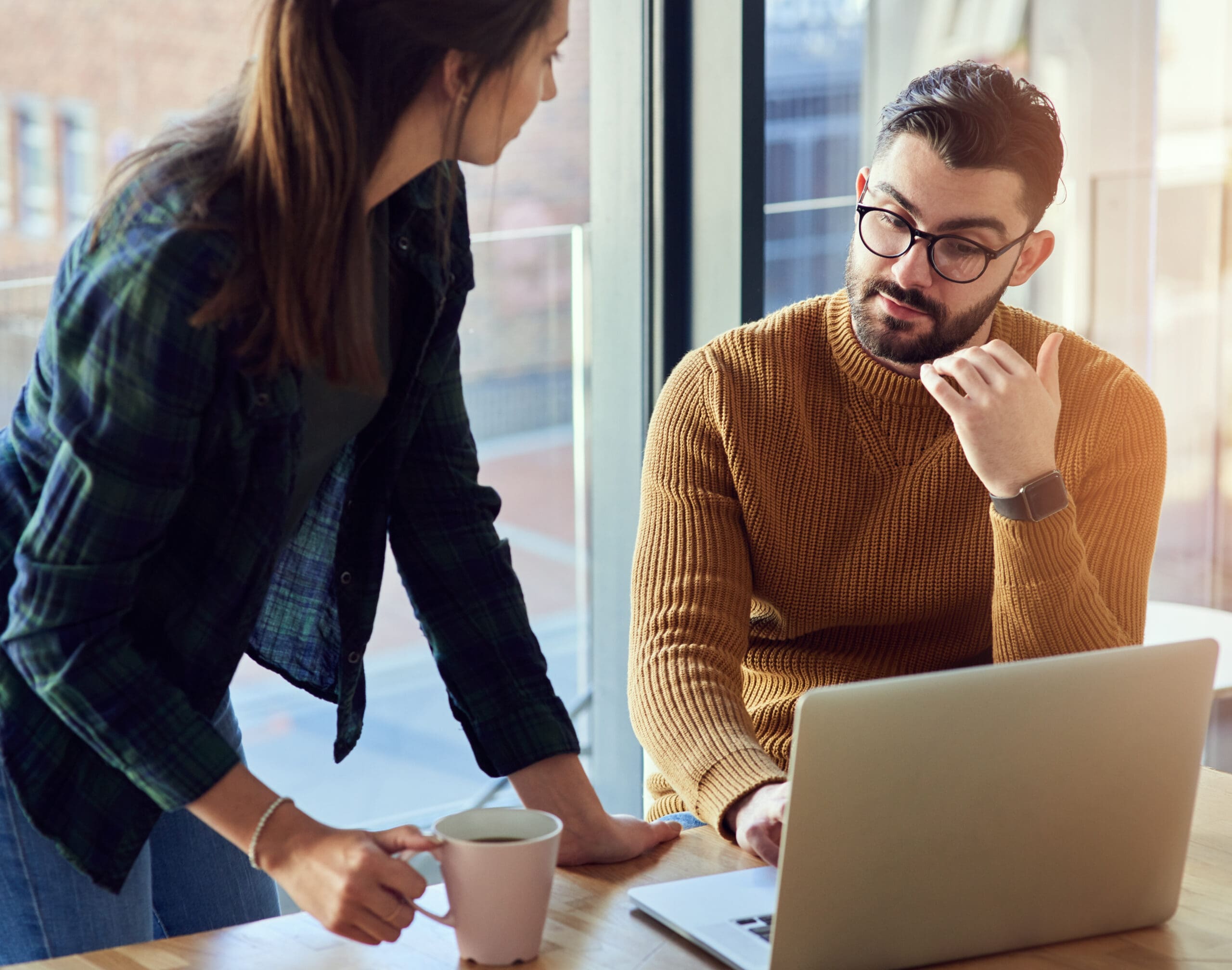 Photo d’un jeune homme d’affaires et d’une jeune femme d’affaires utilisant un ordinateur portable ensemble dans un bureau moderne.